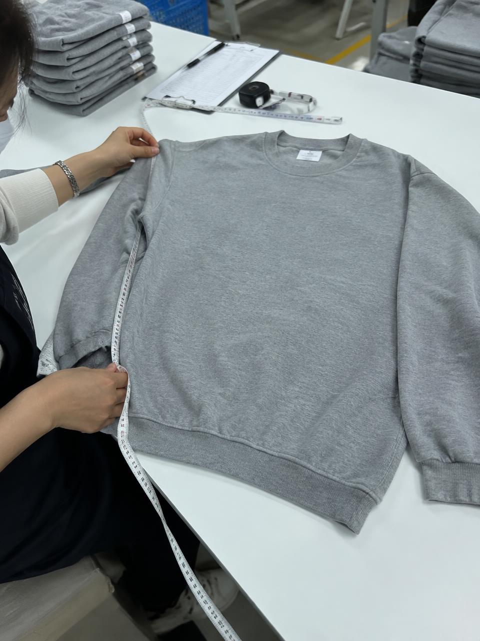 Contrôle qualité d'un sweat gris posé sur une table